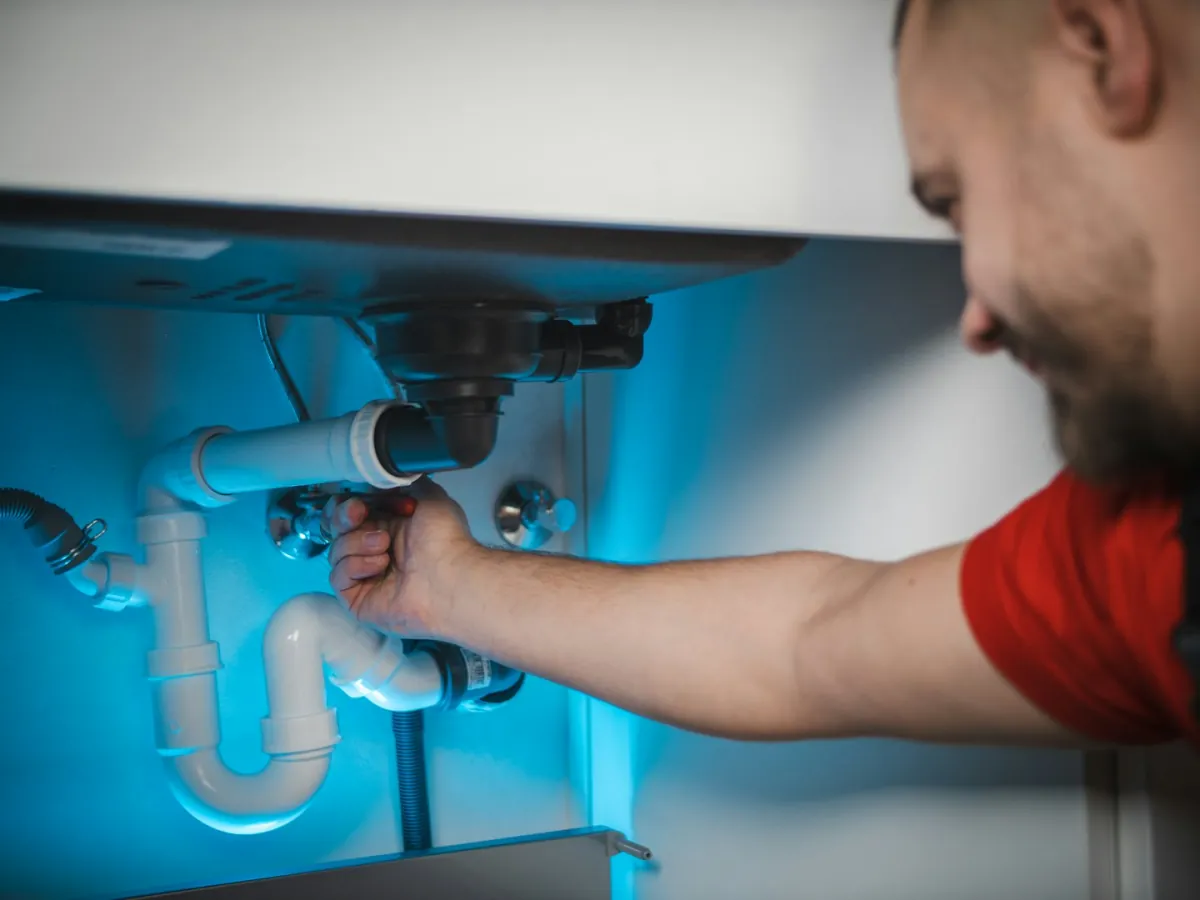 Monteur arbeitet an der Siphonverrohrung unter einem Waschbecken